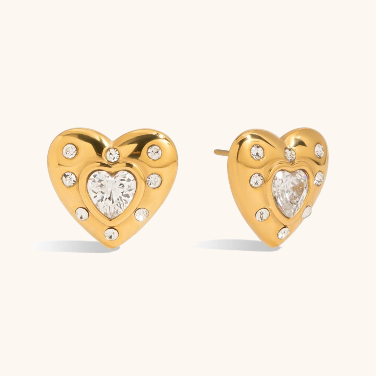 Gold heart-shaped stud earrings with central CZ stones, worn on ear for daily glam look