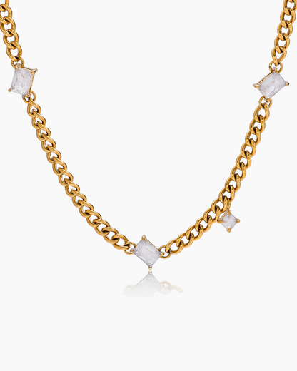 Gold chain necklace with square-shaped white stones on a white background