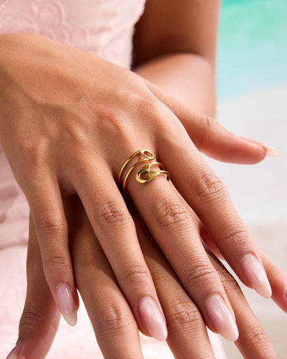 Close-up of model wearing bold gold safety pin ring by the poolside