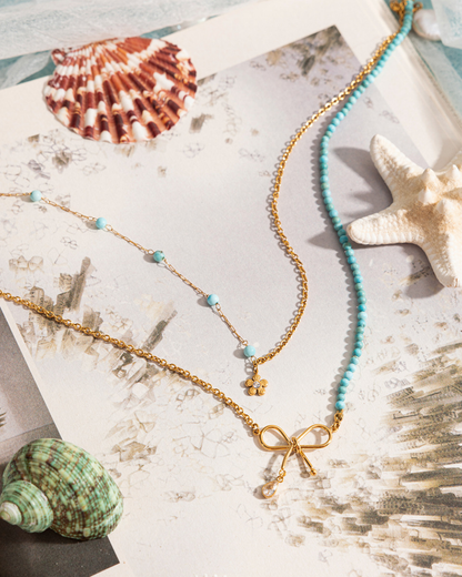 Necklace with a bow pendant on a textured surface with shells and starfish