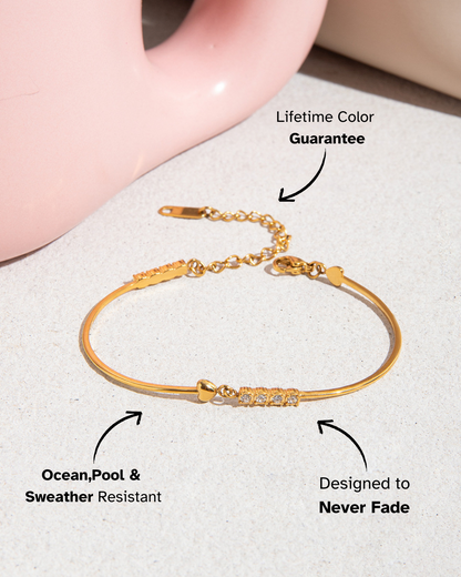 Gold bracelet on a light surface with text highlighting features