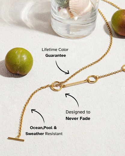 Gold necklace on a white surface with text highlighting features