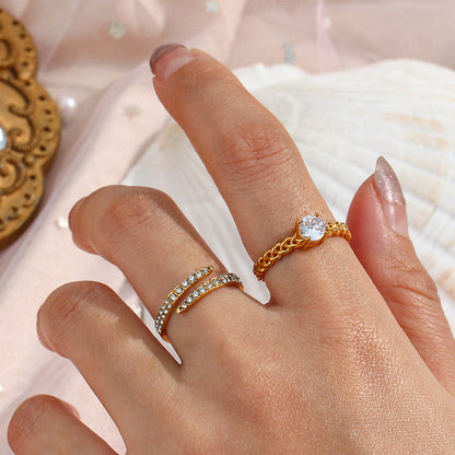 Gold crystal ring styled on hand with other gold rings on beach-inspired backdrop
