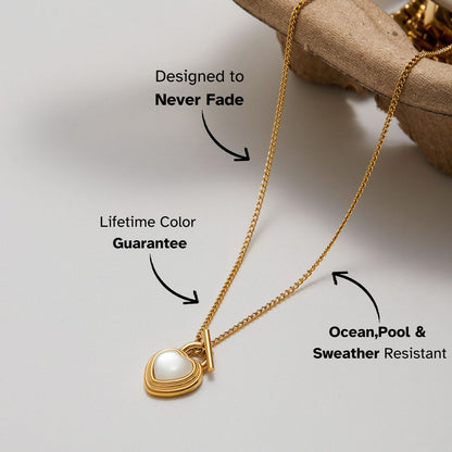 Gold heart pendant necklace with pearl center, shown close-up on neutral background
