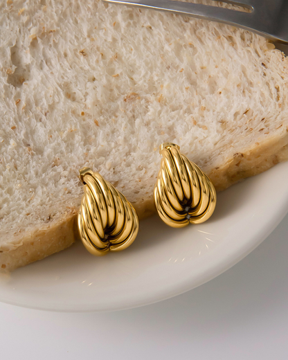 Gold earrings on a slice of bread with a knife