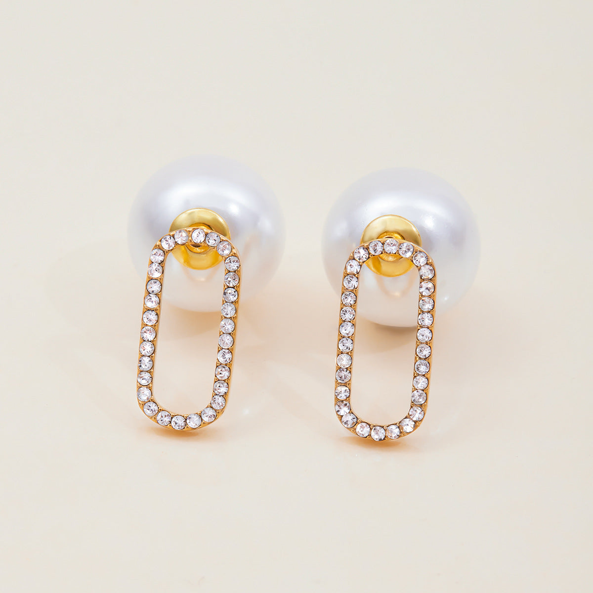 Elegant gold and pearl drop earrings on neutral background