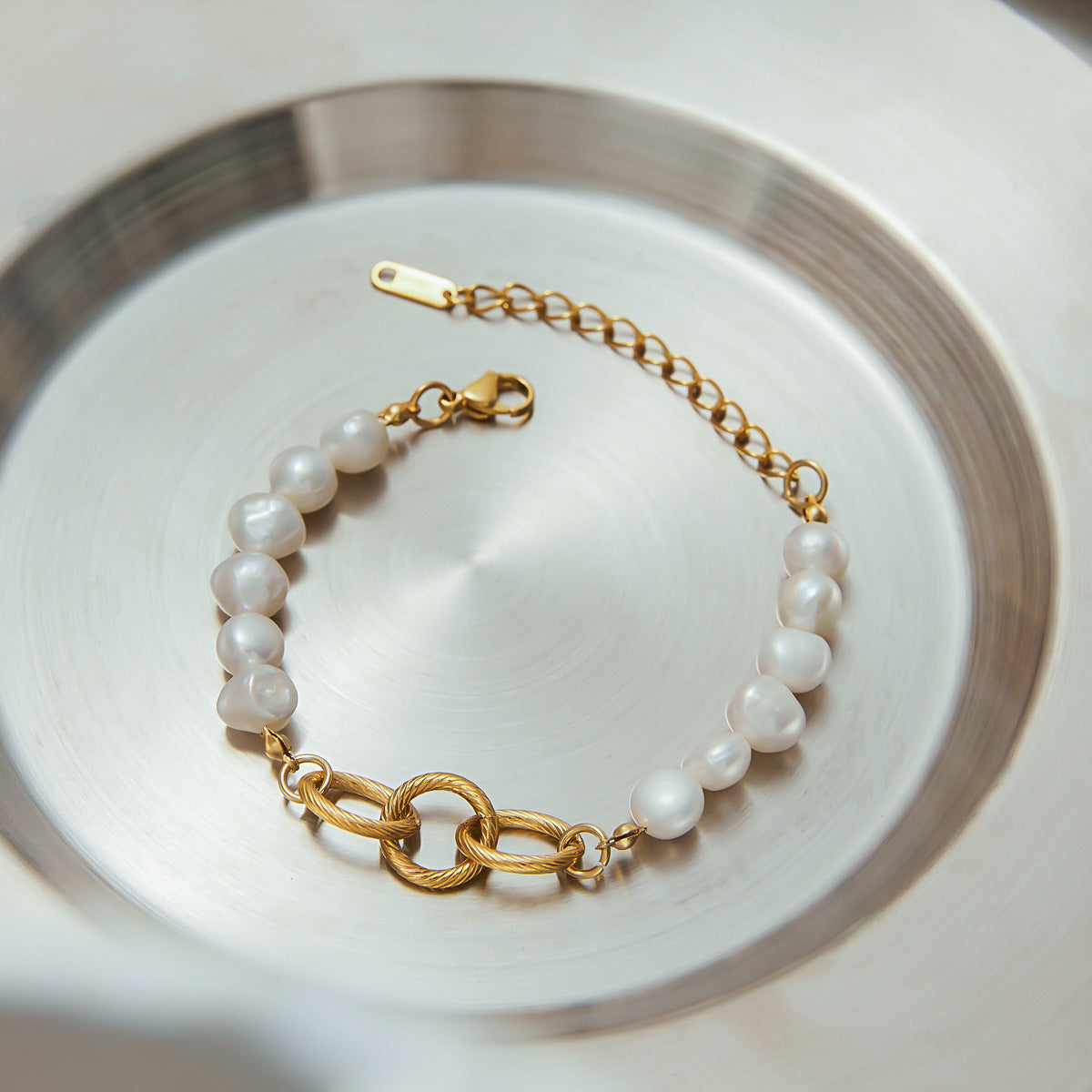 Pearl and gold bracelet displayed in a silver-toned serving tray