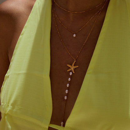 Model showcasing long pearl drop necklace with gold layers by the poolside
