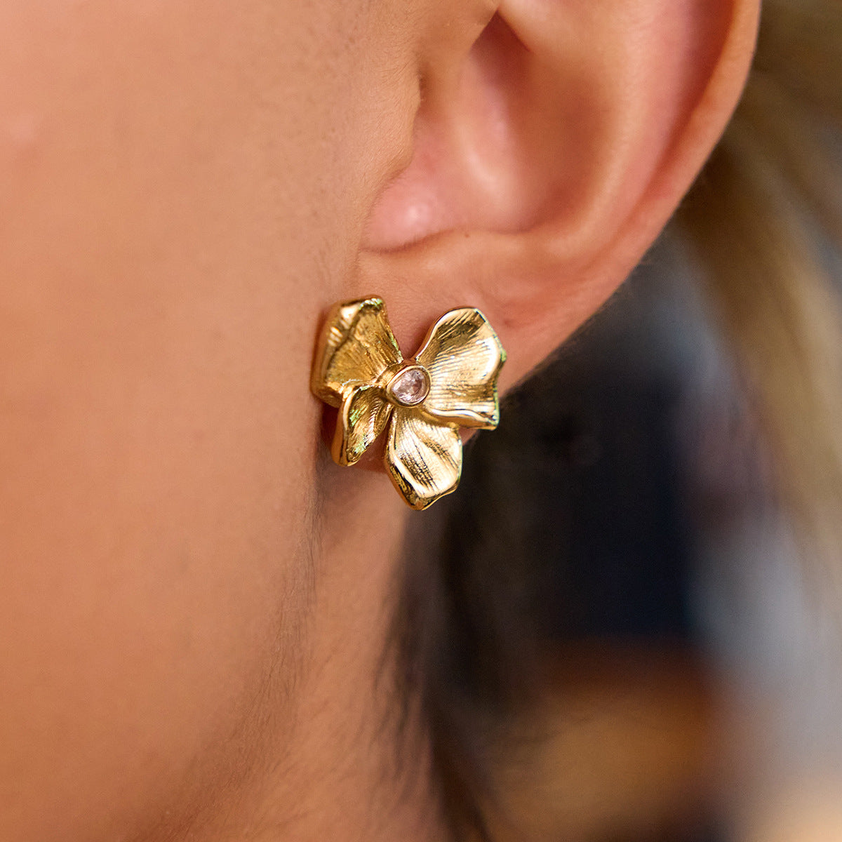 model wearing gold flower studs