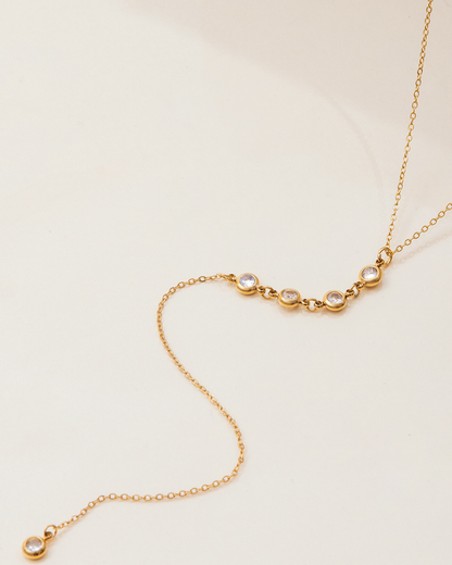 Gold necklace with small round pendants on a beige background