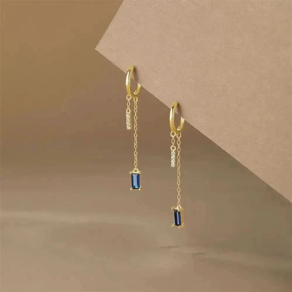 Elevate your outfit with these stylish gold earrings featuring dangling blue gems.