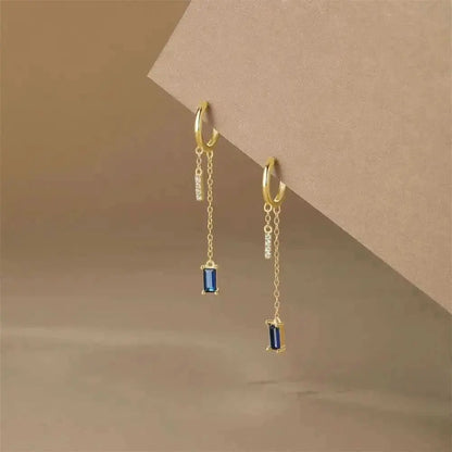 Elevate your outfit with these stylish gold earrings featuring dangling blue gems.