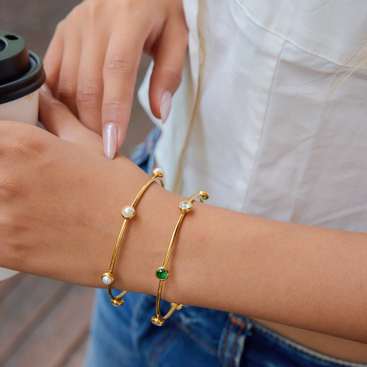 Model stacking green gemstone and pearl bangles