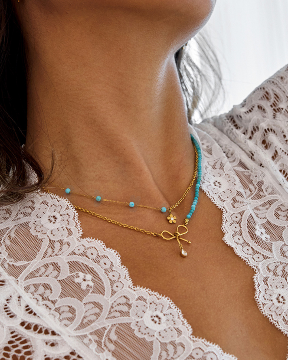 Necklace with blue beads and gold bow on a lace garment