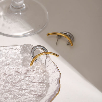 Gold and silver waterproof hoop earrings on textured glass plate