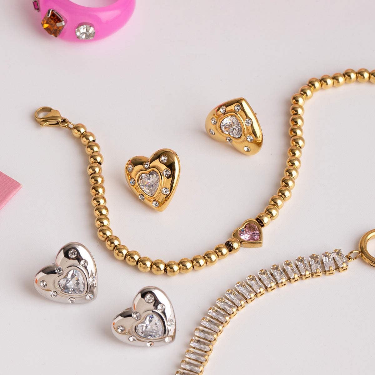 Gold and silver earrings styled with trendy bracelets and pink accessories for modern chic