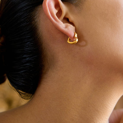 Side profile view of a model wearing polished gold heart hoops, ideal for daily styling