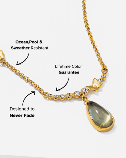 Gold necklace with a teardrop pendant on a white background