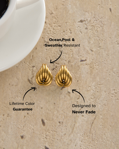 Gold earrings on sand with text highlighting features