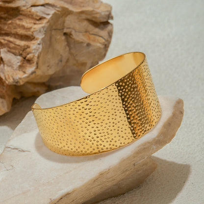Gold bracelet with textured surface on a stone surface