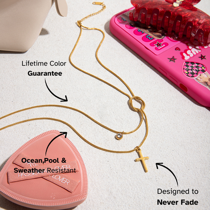 Gold necklace with a pink heart-shaped product and pink phone on a light surface
