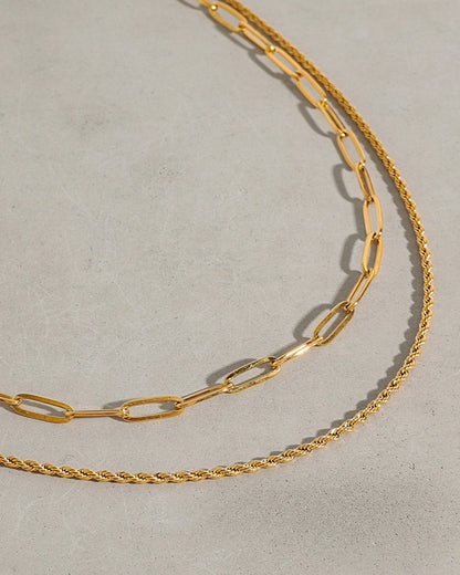 Two gold chains on a light gray background