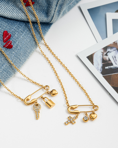 Gold necklaces with charms on a white surface with denim fabric and photos in the background