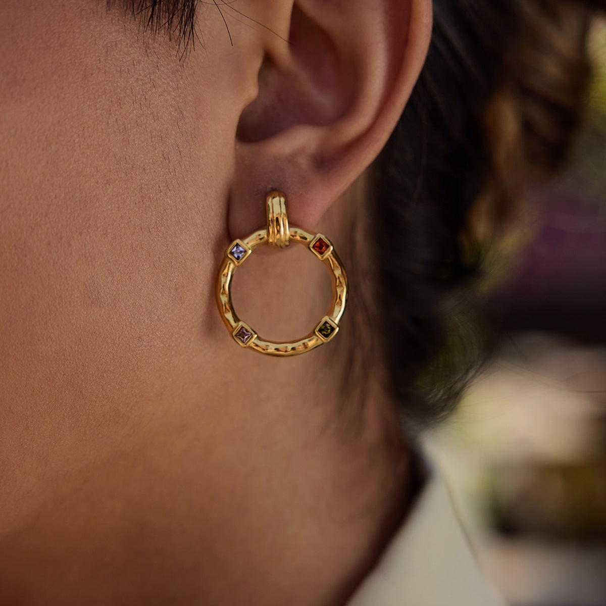 Model wearing vibrant gold round earrings with square-set crystals