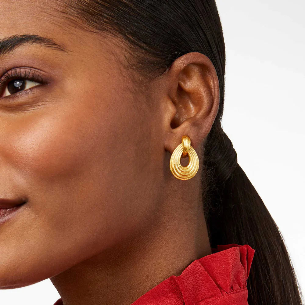 Smiling model with ponytail wearing teardrop gold earrings with red blouse
