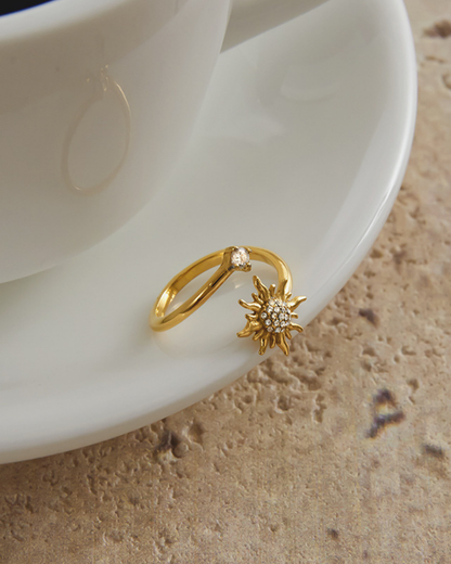 Gold ring with sun design on a white ceramic plate