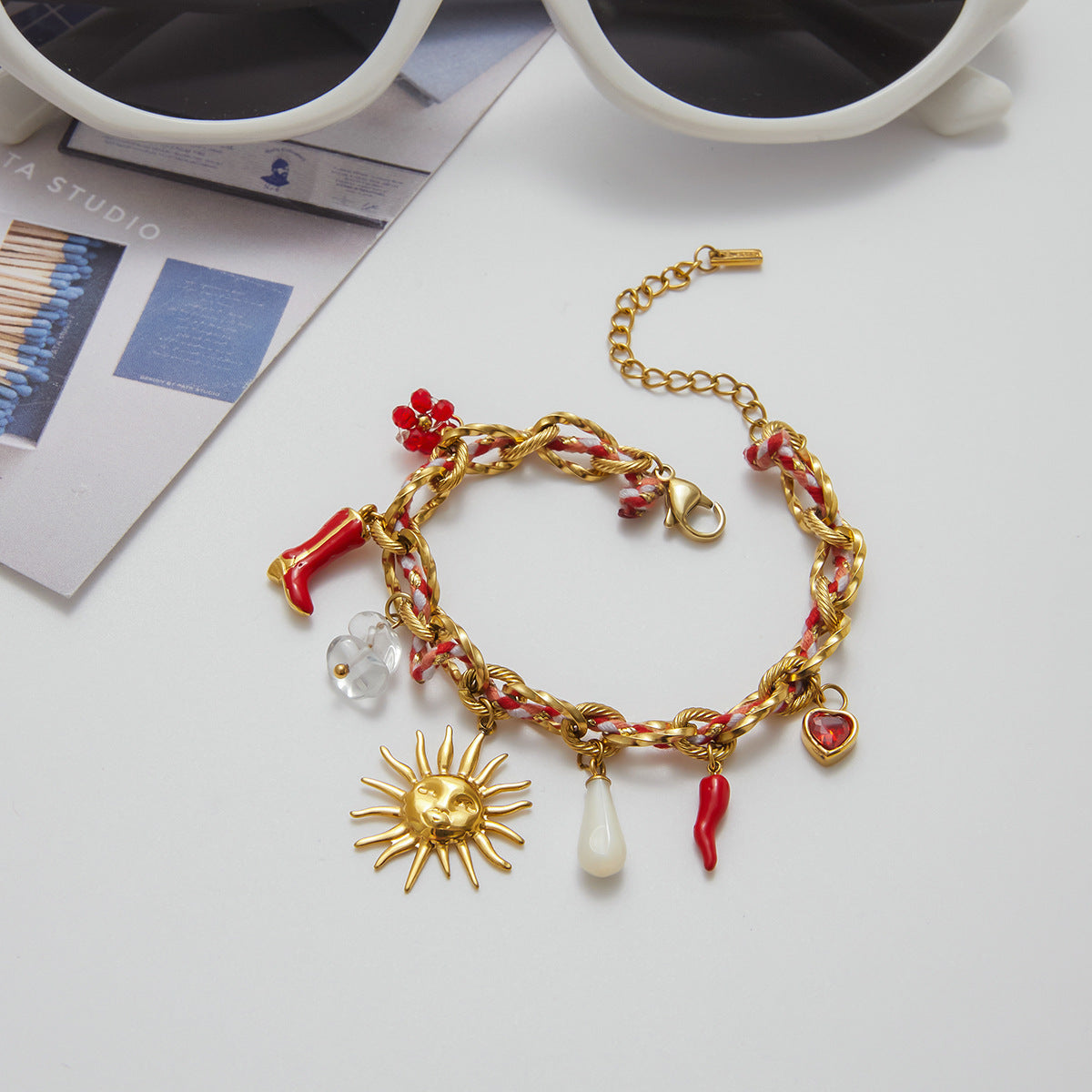 Gold bracelet with charms on a white surface with coffee cups in the background