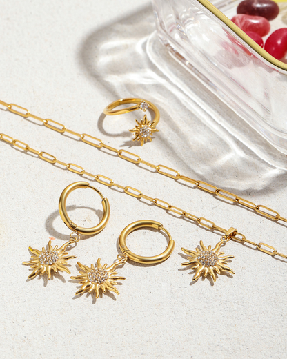 Gold jewelry set including necklaces, rings, and earrings on a light background.