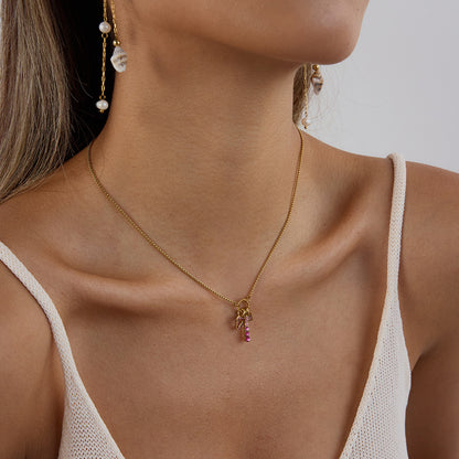 Model wearing the pink charm necklace styled with a white tank top