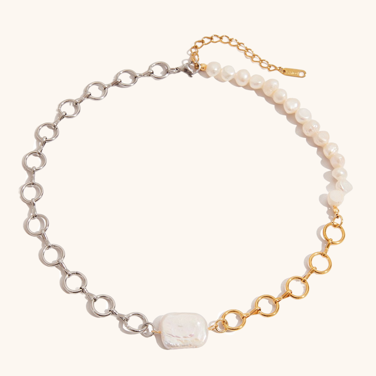 Product image of mixed metal and pearl necklace with asymmetric design on white background