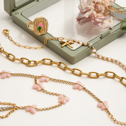 Flat lay of pink butterfly hand bracelet with gold chain, whimsical summer jewelry