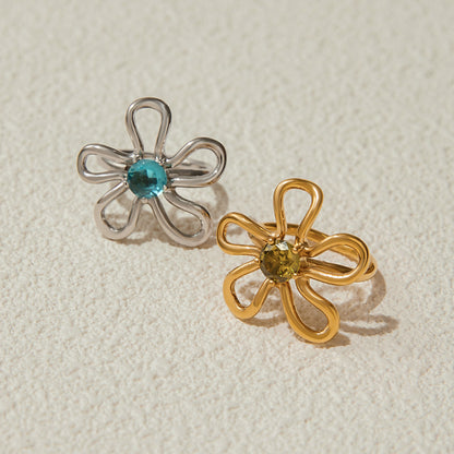set of gold and silver floral rings with gemstones on textured background