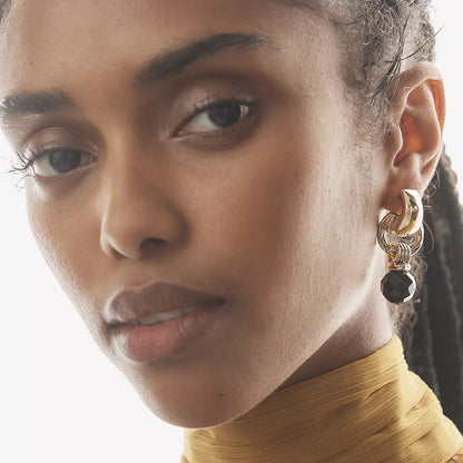 Close-up of chunky black gem and gold link earrings on ear