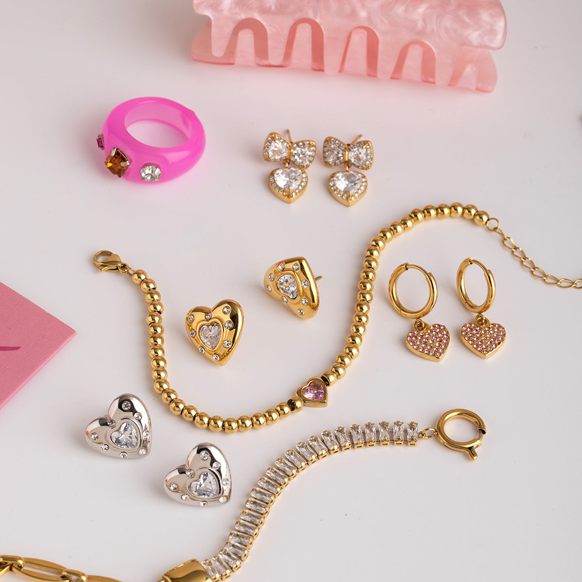 Gold bow and heart drop earrings with white crystal center, product display on neutral background