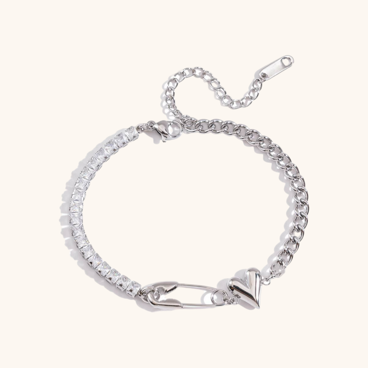 Close-up of silver safety pin bracelet with heart charm and rhinestone chain on white background