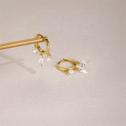 Lifestyle photo of dangling gold hoops with round and cone-shaped crystals