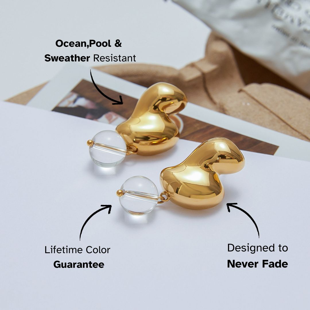Shiny heart-shaped gold earrings with clear orb detail