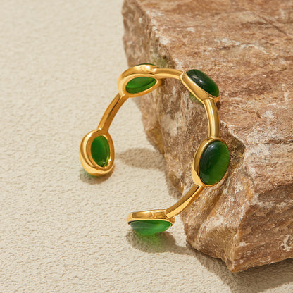Polished gold and green bangle resting on natural stone background