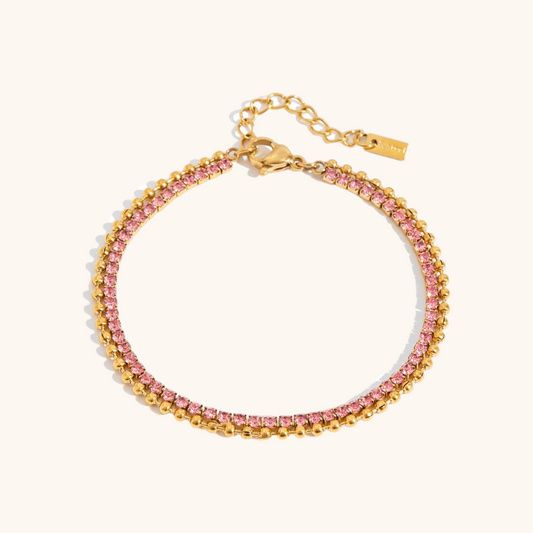 Close-up of gold bracelet with pink rhinestones on a white background