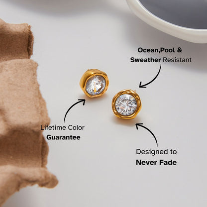 Bold crystal stud earrings placed near sunglasses and coffee cup