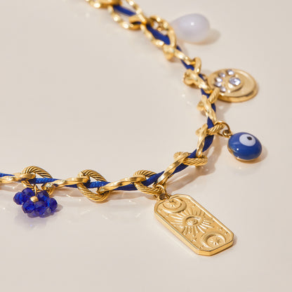 Detail view of sun-engraved gold tag on chunky blue woven necklace