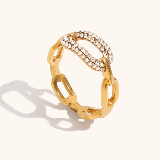 Bold gold chain link ring with pavé crystals styled on a modern silver plate.