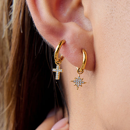 Model wearing gold cross earrings with double piercing style outdoors