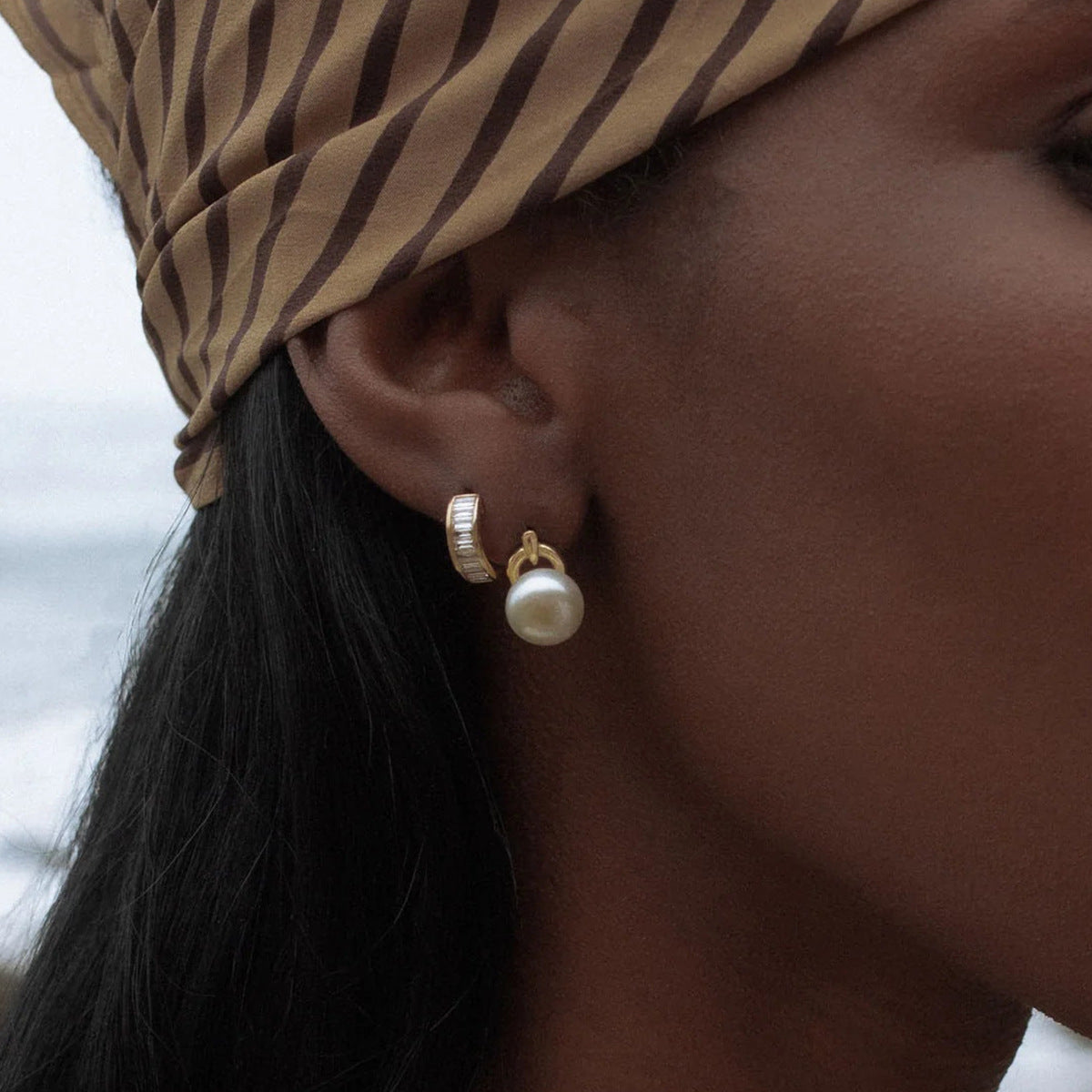 Model wearing minimalist gold huggie hoop and pearl charm