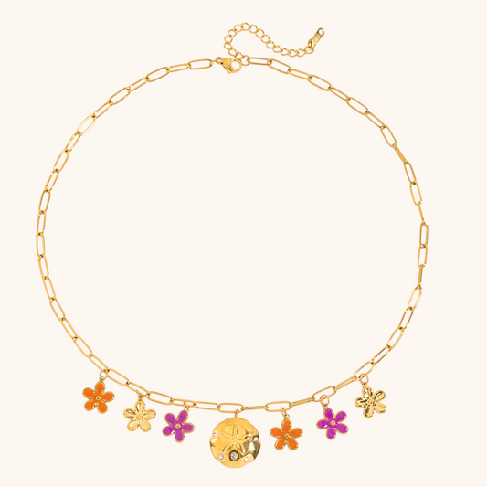 Still life of enamel flower charm necklace on paperclip chain, highlighting colorful details and golden finish.
