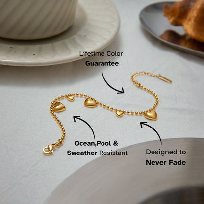 gold beaded heart bracelet on a ceramic plate